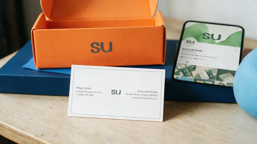 A small business brand kit built around an initial logo, shown on a business card, packaging box, and phone social profile.